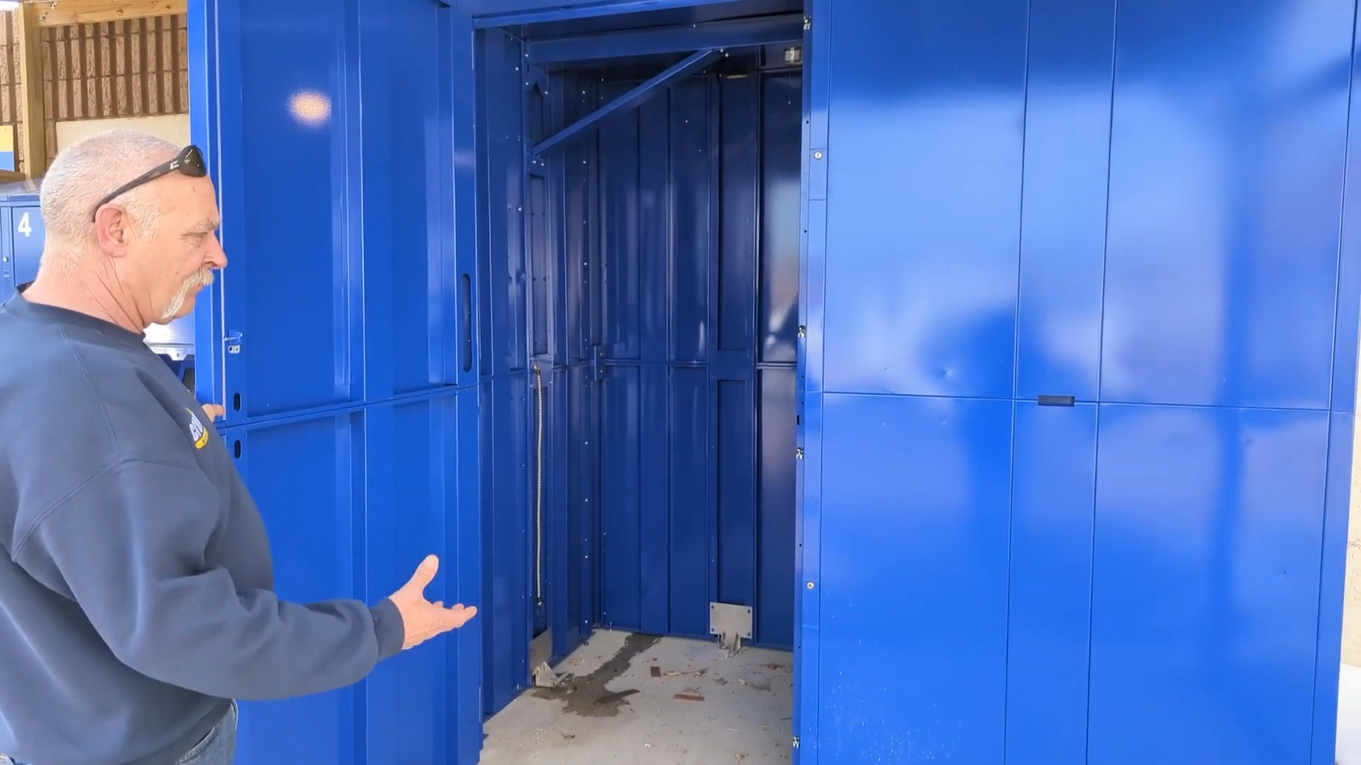 Doug Haas of Crown Rentals holds an extra-large blue rental locker door open.